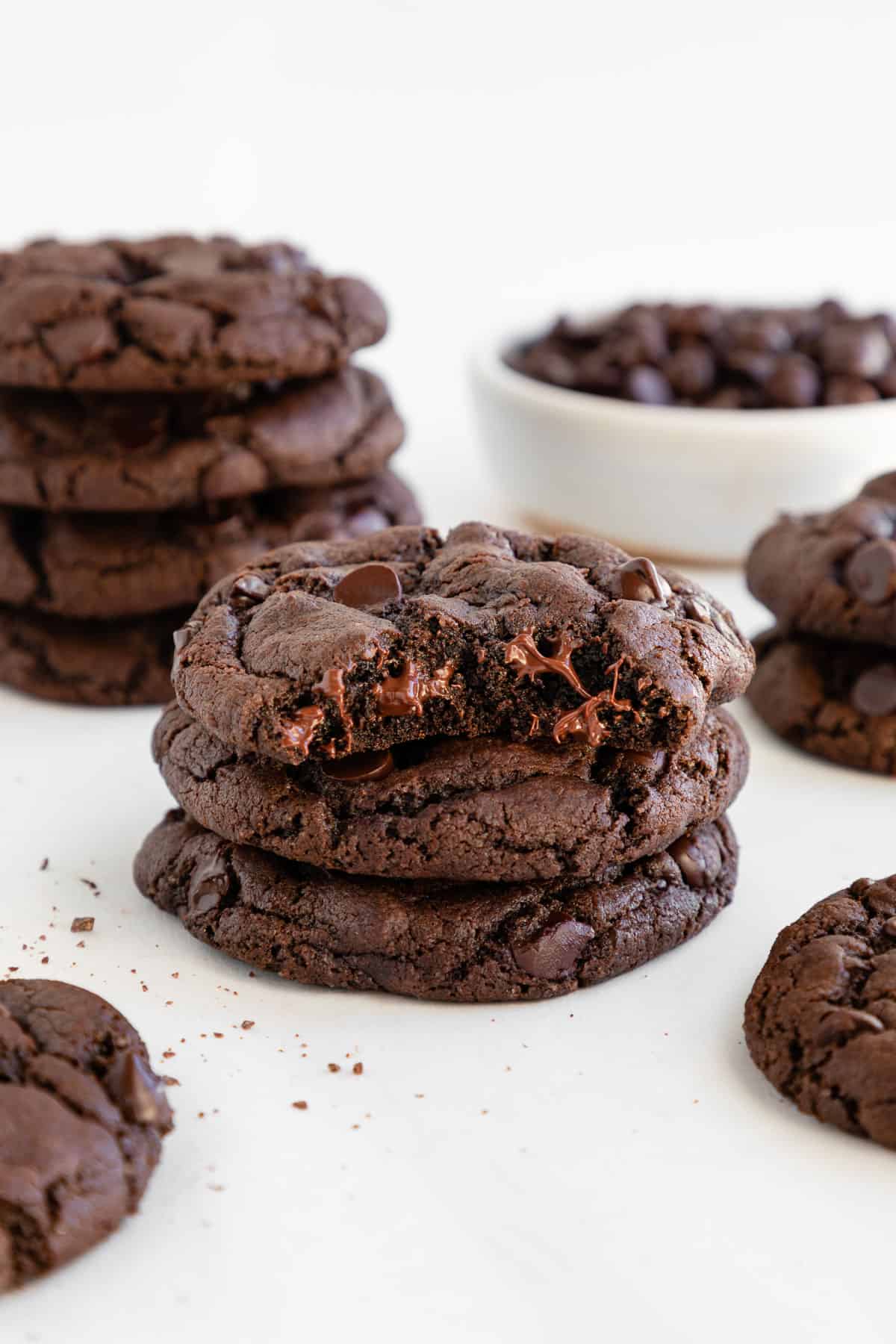 two stacks of vegan double chocolate chip cookies with a bite taken out of the top cookie