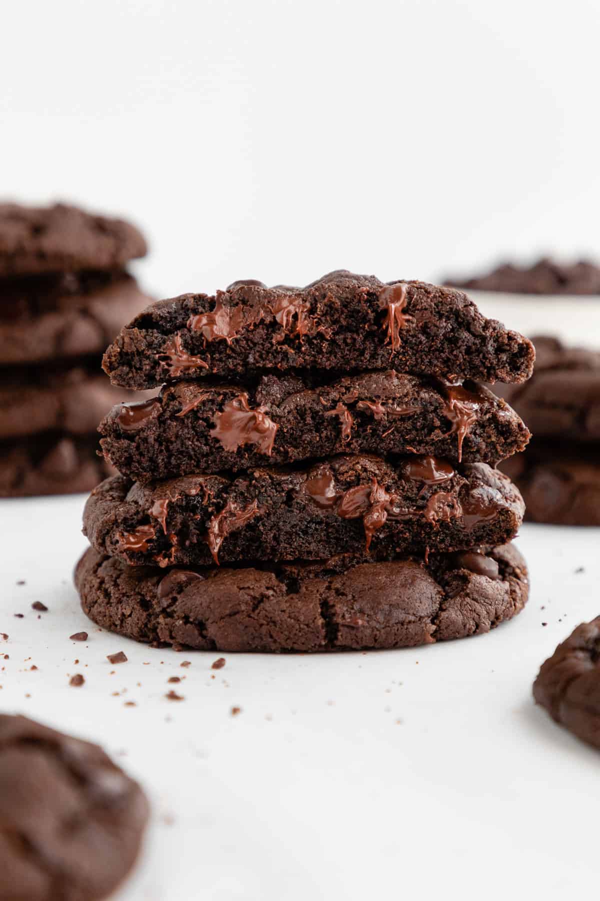 a warm and gooey stack of four vegan double chocolate chip cookies with melted chocolate oozing out of the middle