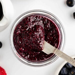 a knife scooping berry chia seed jam out of a glass weck jar