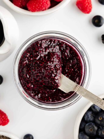 a knife scooping berry chia seed jam out of a glass weck jar