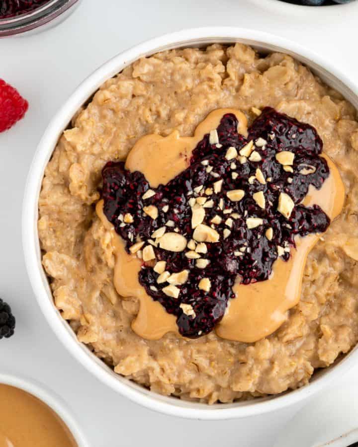 close up image of peanut butter and jelly oatmeal inside a white bowl