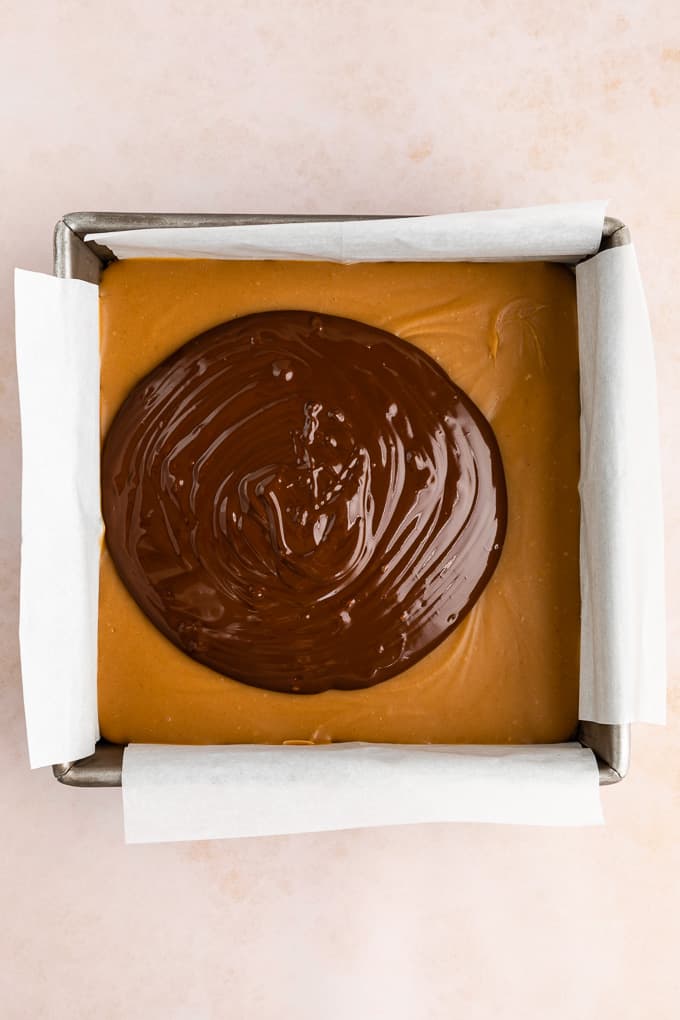 a puddle of melted chocolate on top of a chilled caramel layer in a square baking dish