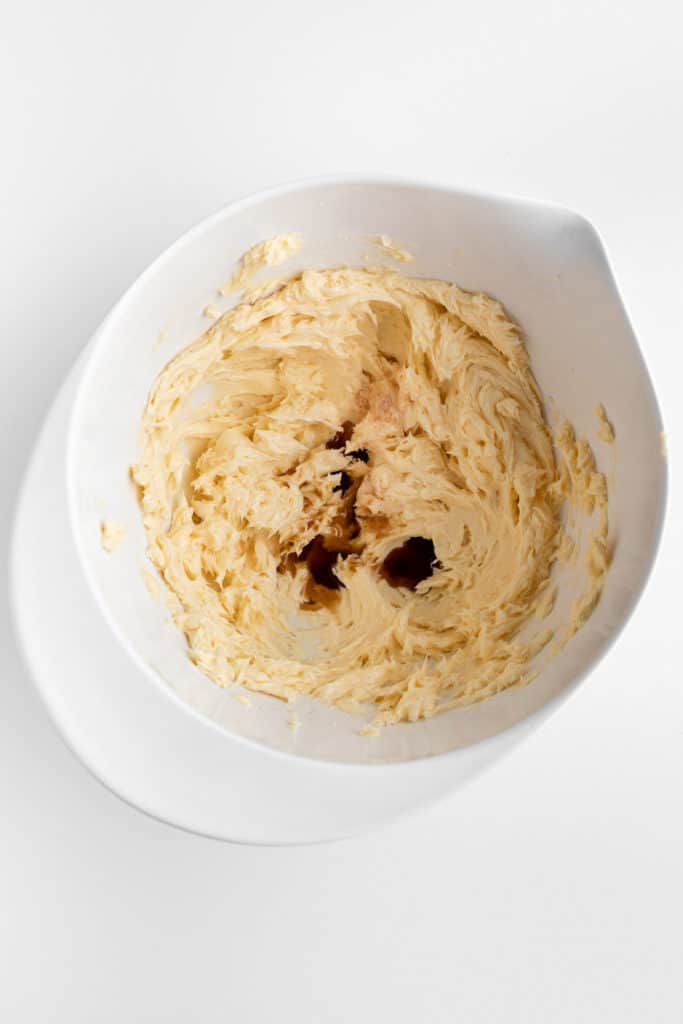 creamed vegan butter and vanilla extract in a white mixing bowl
