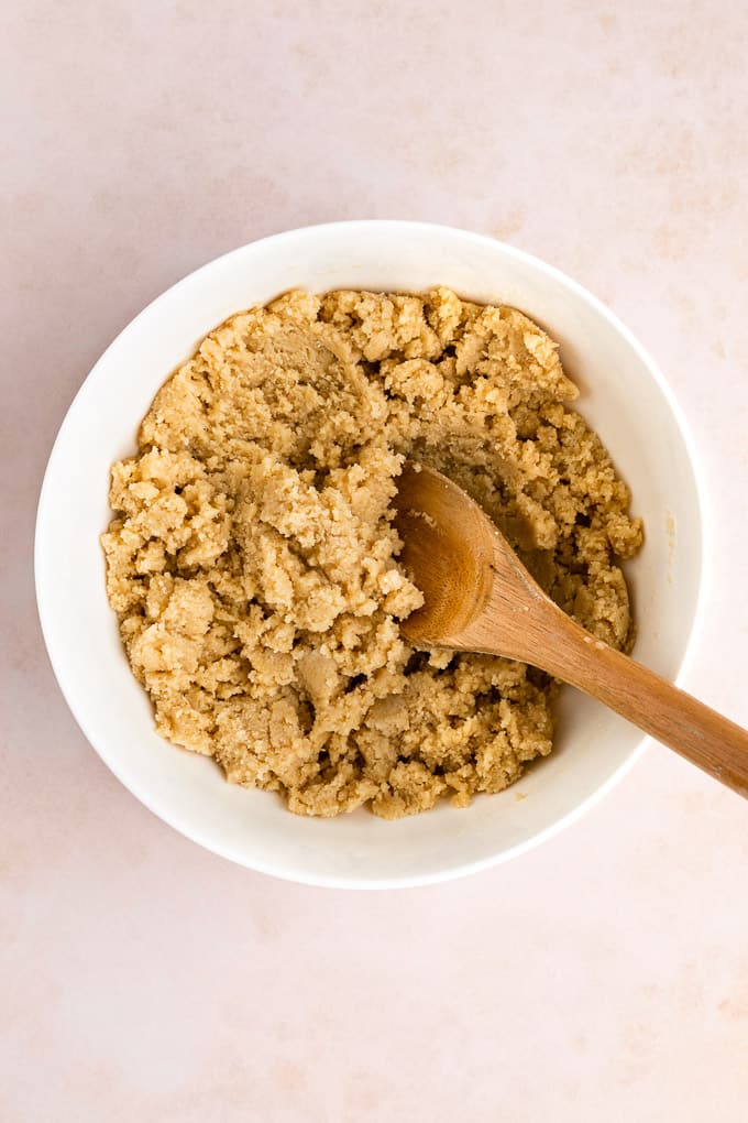 vegan shortbread cookie dough inside a white bowl with a wooden spoon