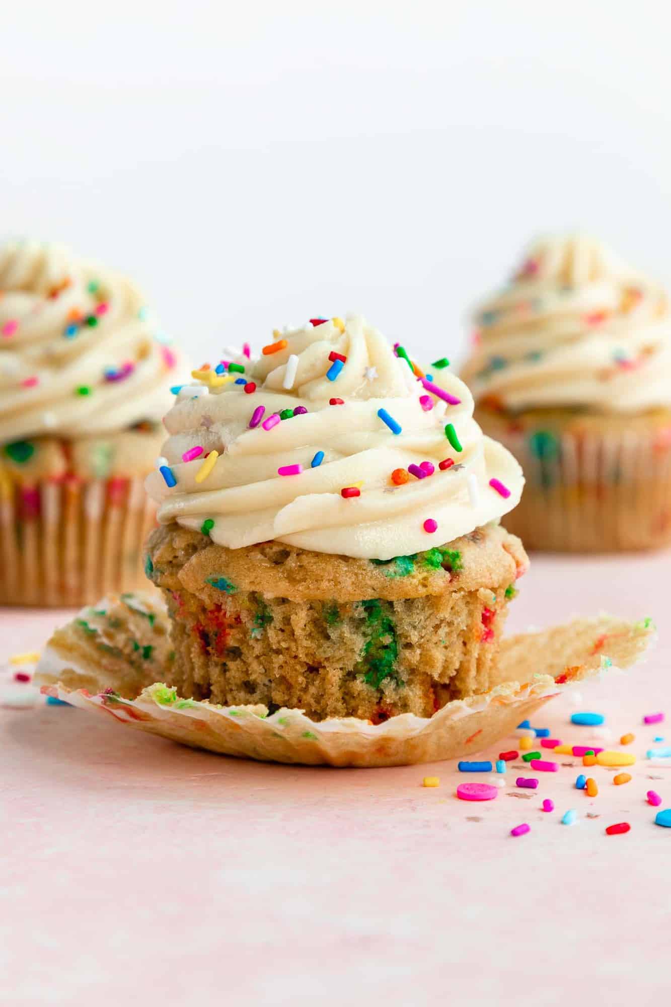 a vegan funfetti cupcakes with vanilla frosting and the cupcake liner peeled off of it