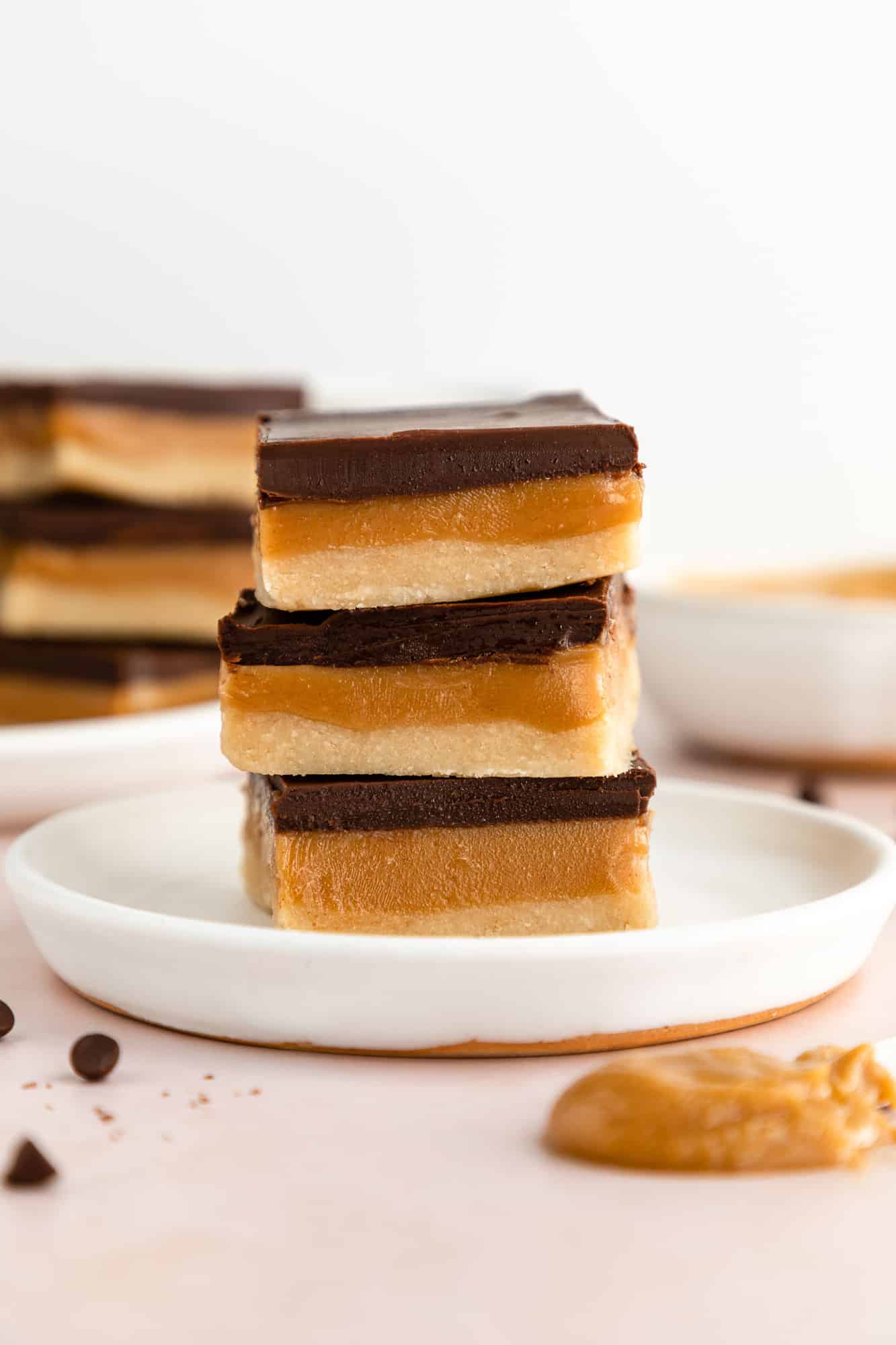 three no-bake vegan millionaire shortbread bars stacked on a white plate