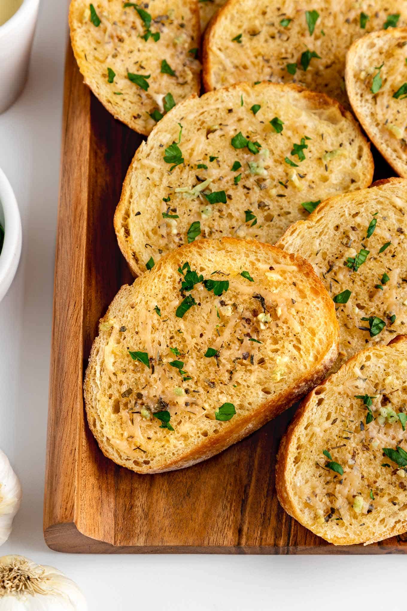 vegan garlic bread on a wooden board with parmesan and parsley