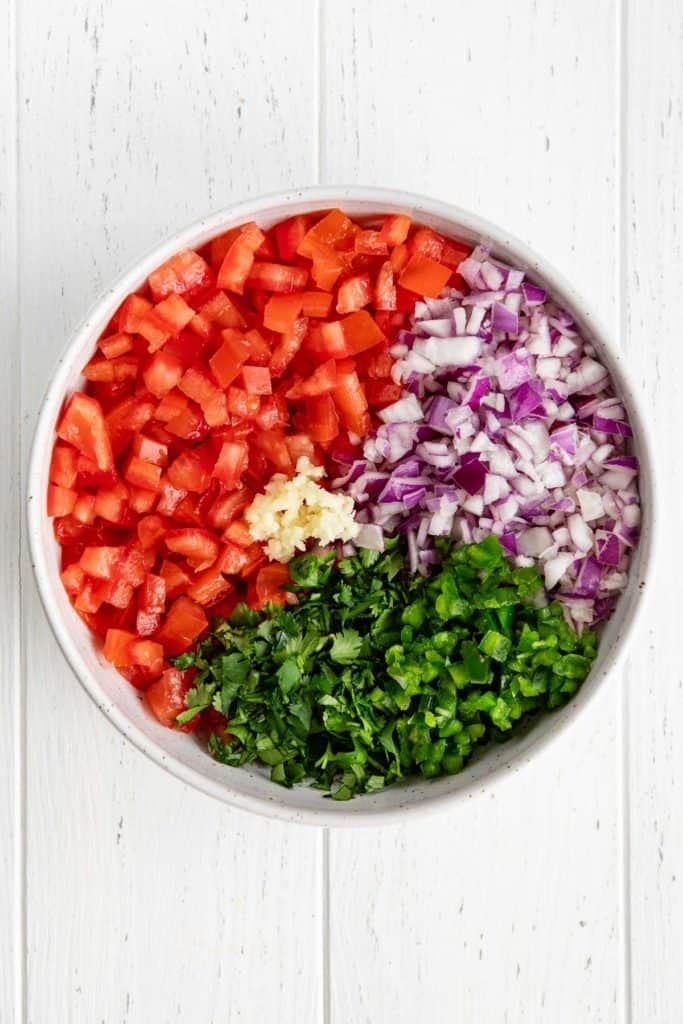 tomatoes, red onion, cilantro, jalapeño, and garlic in bowl