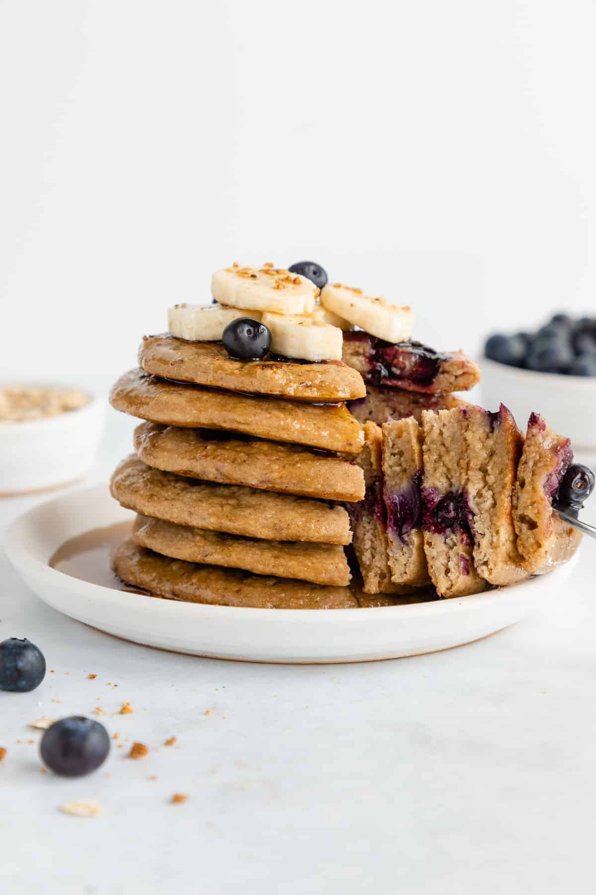 a stack of sliced vegan blueberry banana pancakes on a white plate