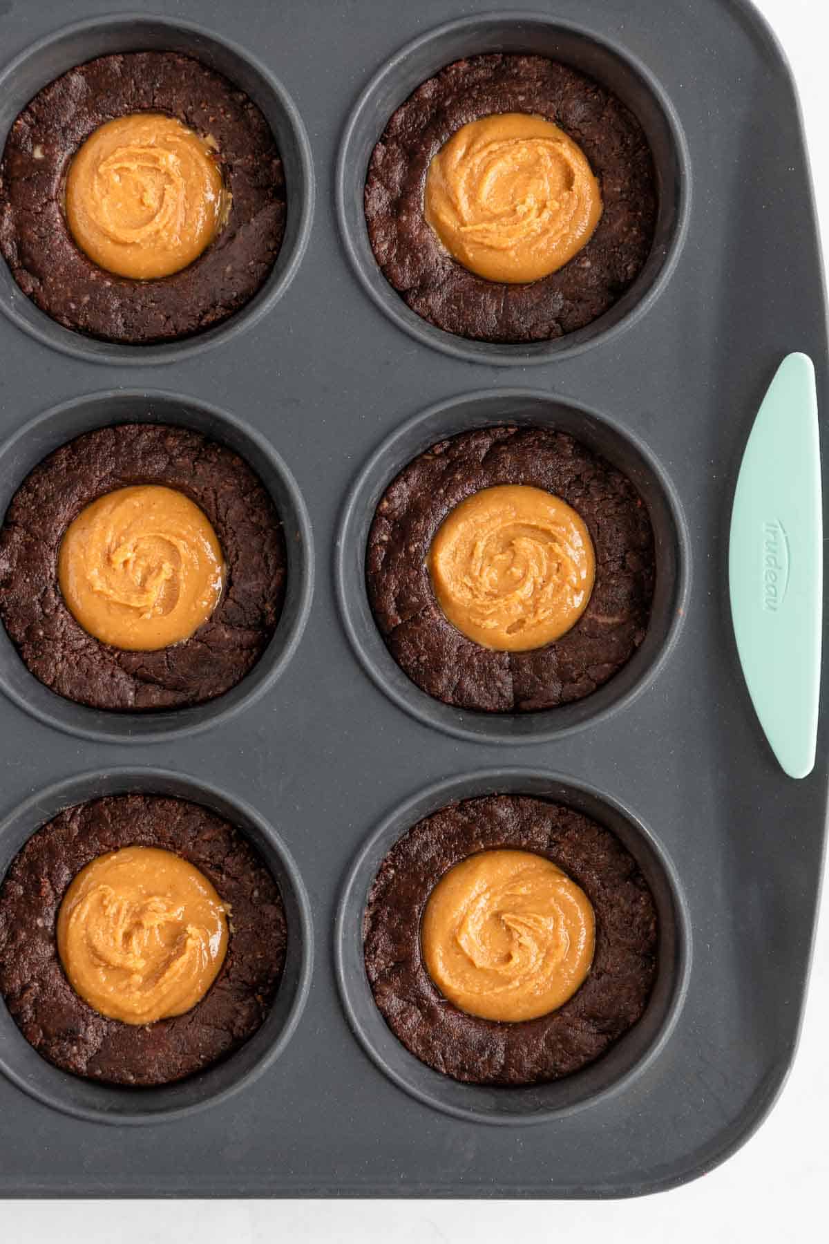 peanut butter brownie cups inside a silicone muffin tin