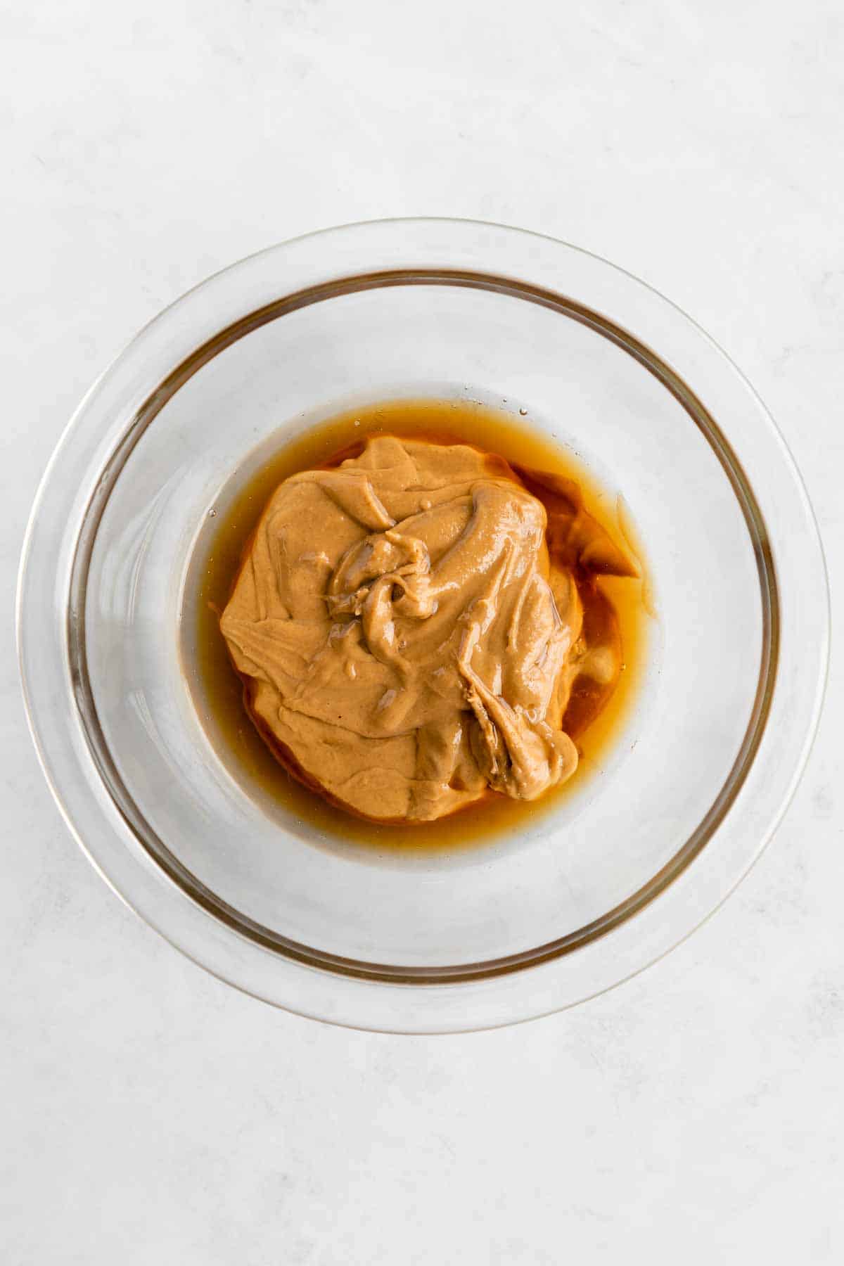 peanut butter and maple syrup in a glass pyrex mixing bowl