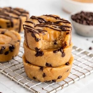 a stack of three vegan caramel cookie dough cups with a bite taken out of the top cup