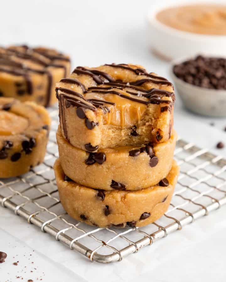 a stack of three vegan caramel cookie dough cups with a bite taken out of the top cup