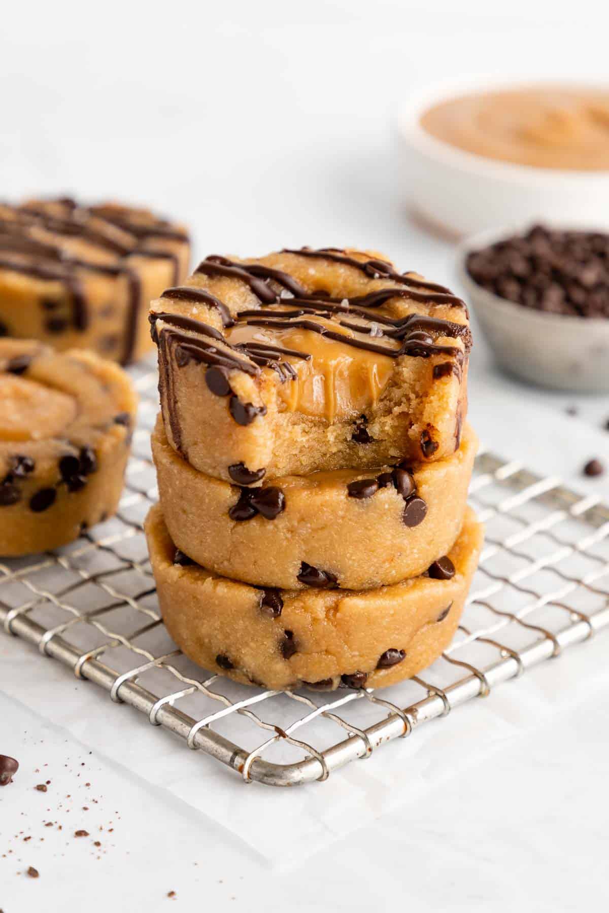 a stack of three vegan caramel cookie dough cups with a bite taken out of the top cup