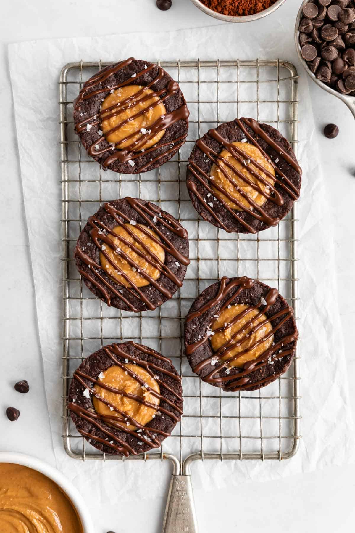 five no bake peanut butter brownie cups on a wire cooling rack beside a bowl of peanut butter