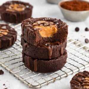 a stack of vegan no bake peanut butter brownie cups on a wire cooling rack with a bite taken out of the top one