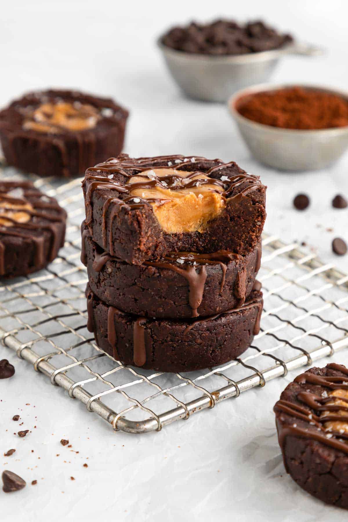 a stack of vegan no bake peanut butter brownie cups on a wire cooling rack with a bite taken out of the top one