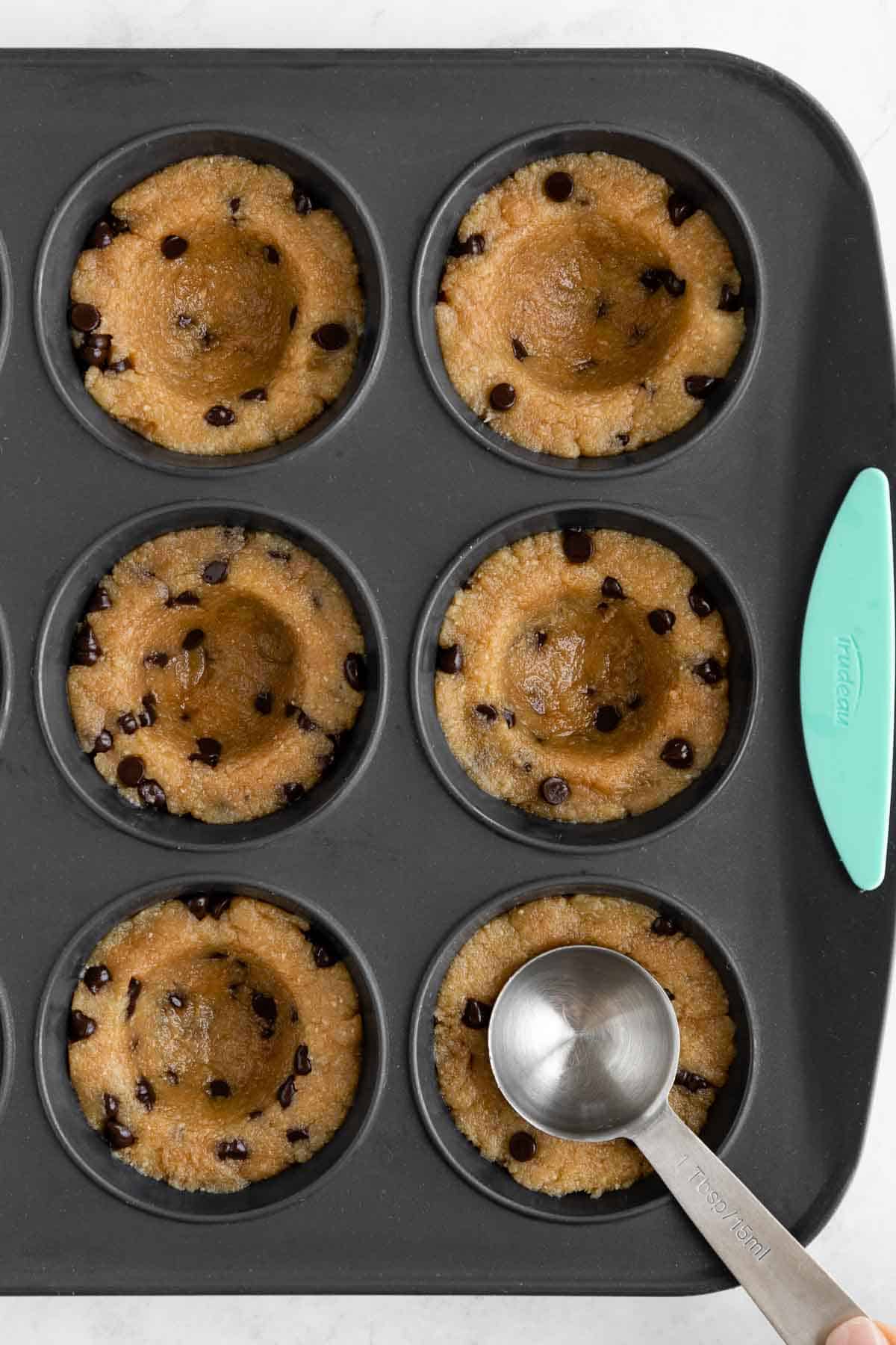 creating wells in healthy edible cookie dough in a grey silicone muffin pan