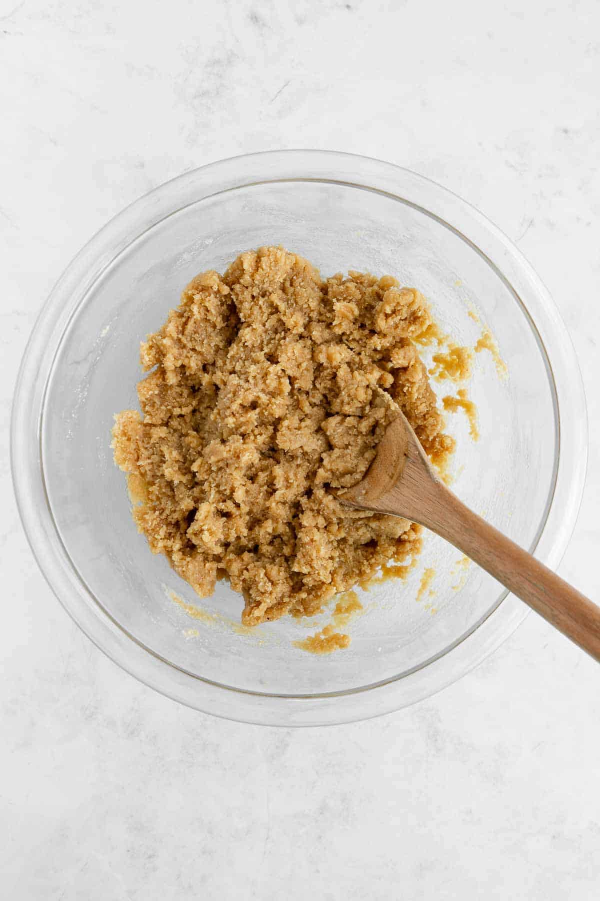 a wood spoon mixing healthy edible cookie dough in a glass bowl