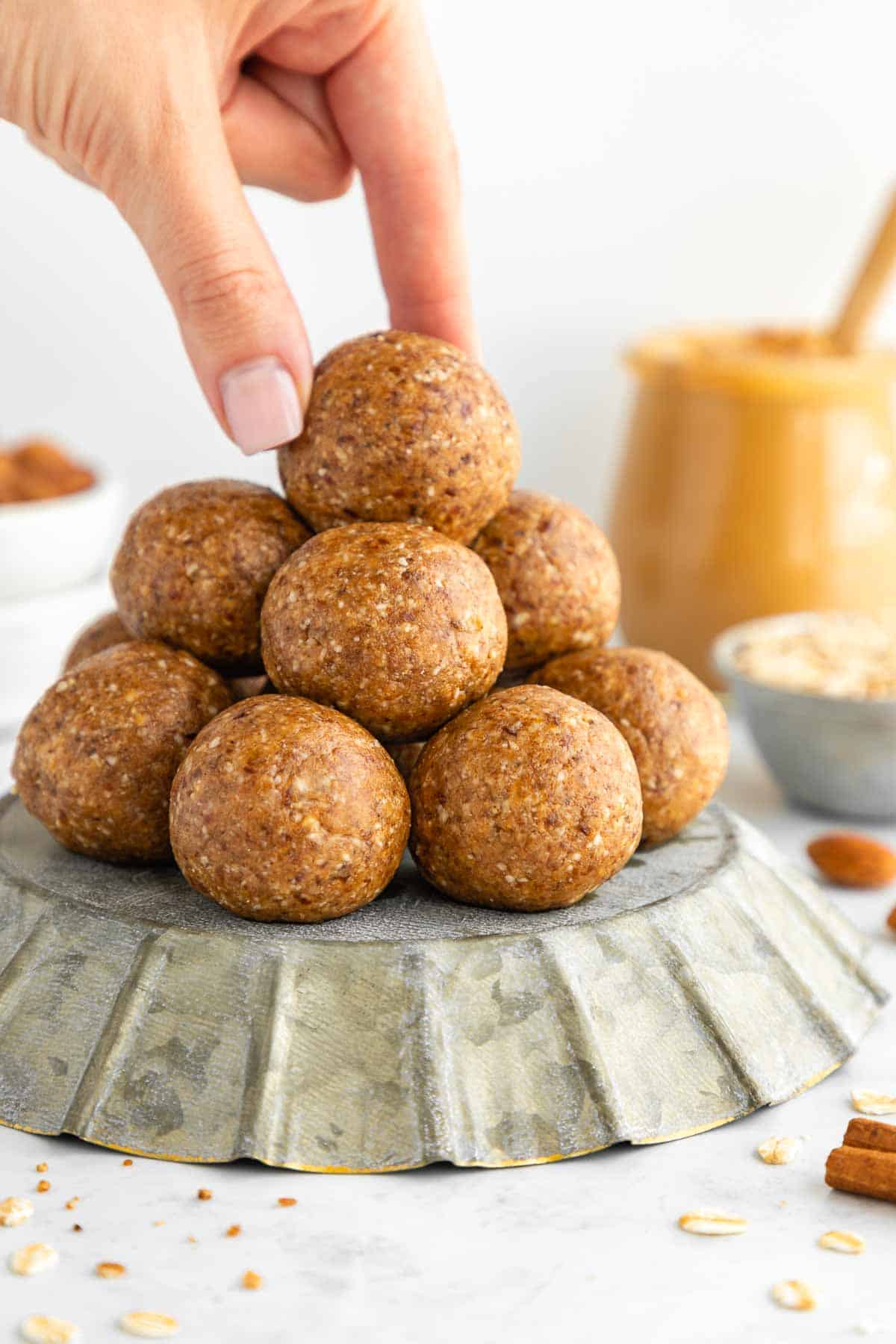 a hand grabbing a stack of almond butter energy balls on a pie pan