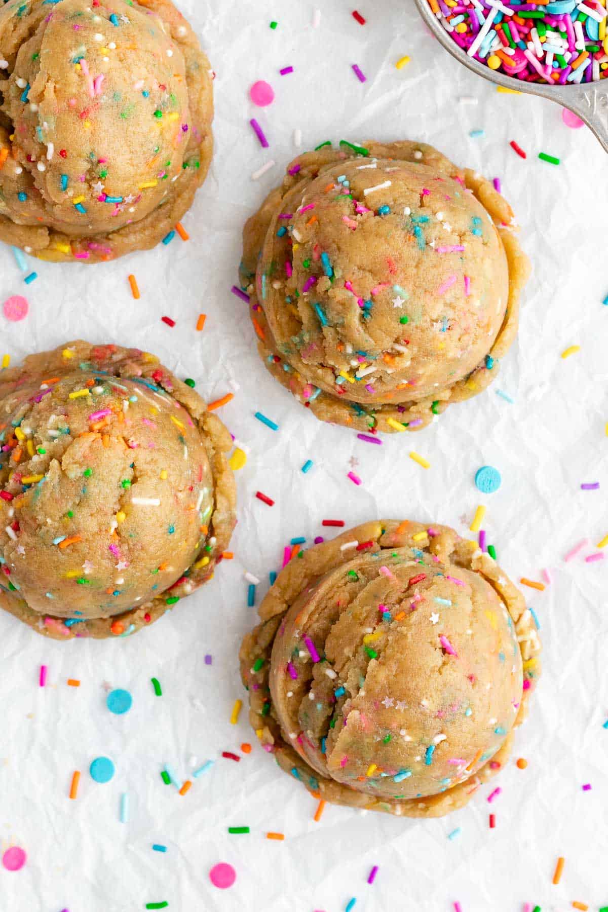 four large rounds of edible funfetti cookie dough with vegan rainbow sprinkles