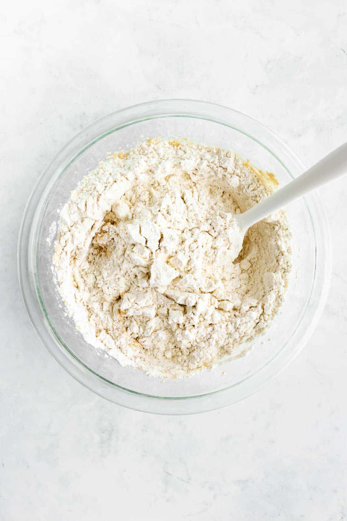 mixing flour into dough in a glass bowl