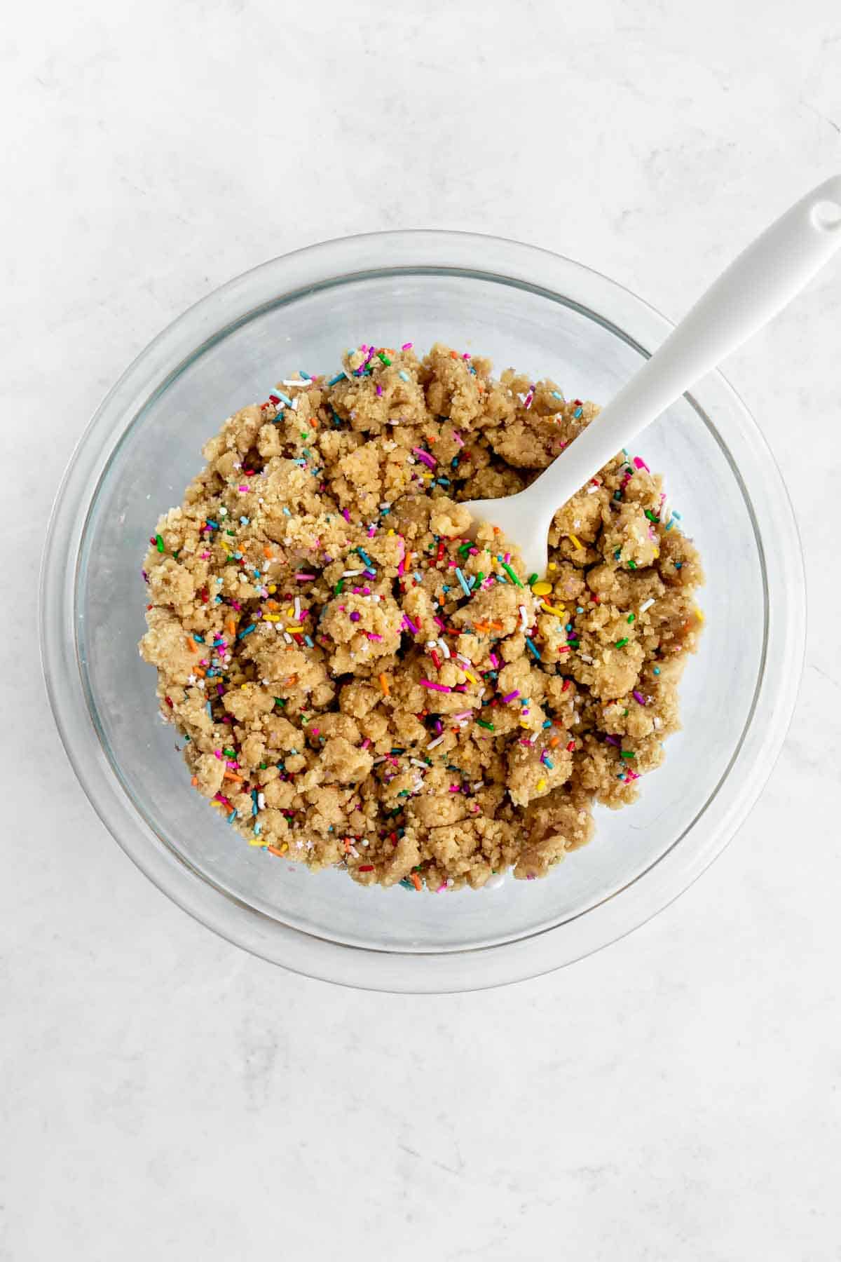 mixing vegan funfetti cookie dough in a glass bowl