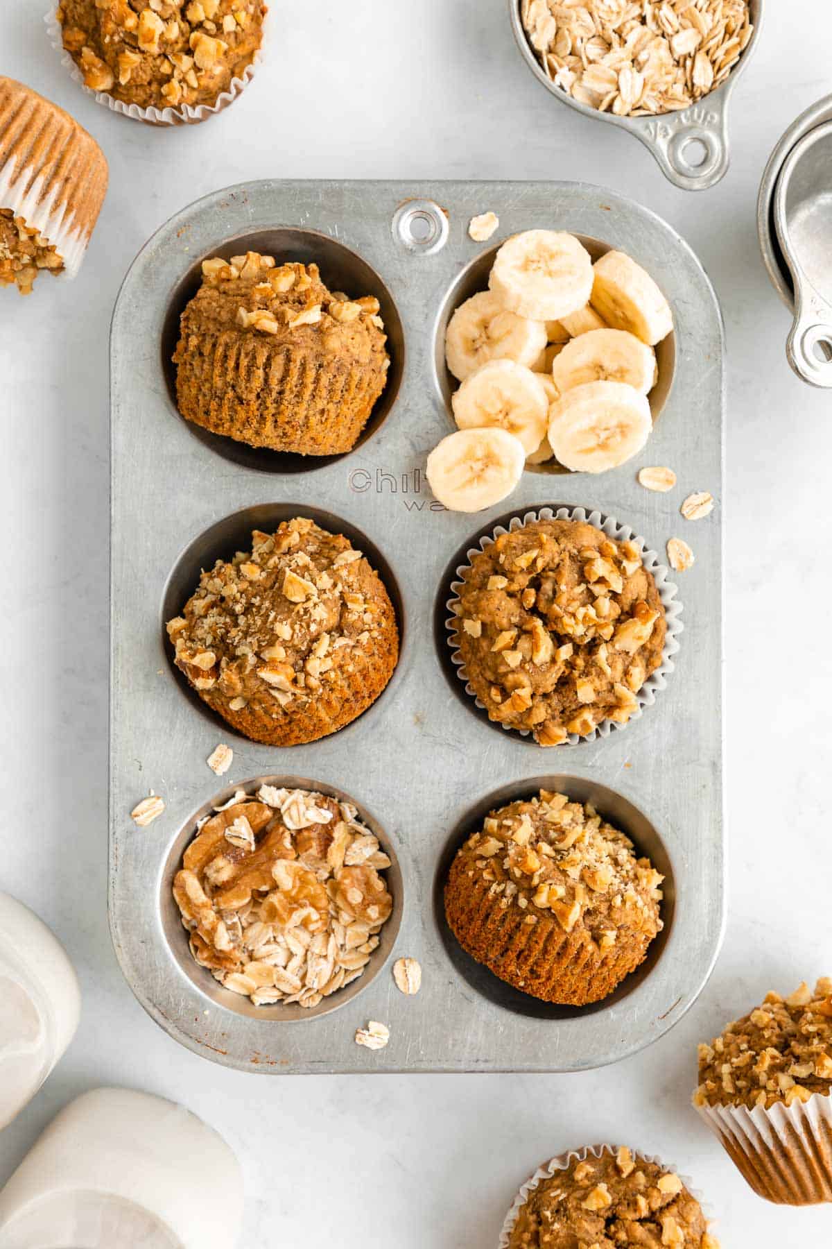 healthy banana nut muffins in a vintage muffin tin with walnuts, oats, and sliced banana