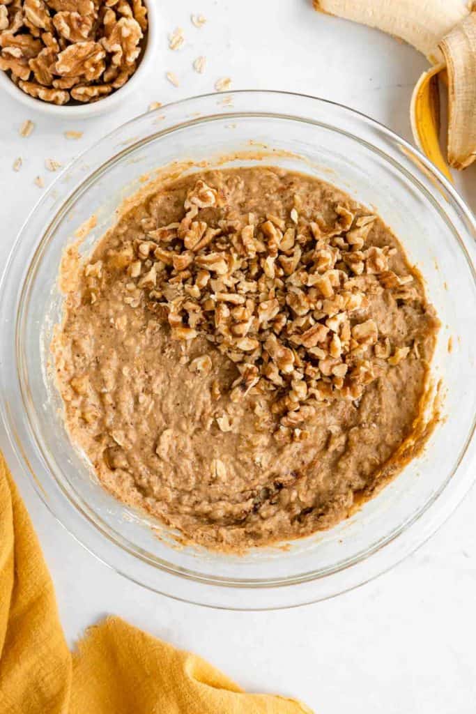 banana nut muffin batter with walnuts in a glass mixing bowl