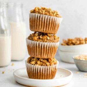 a stack of three vegan banana nut muffins on a white plate
