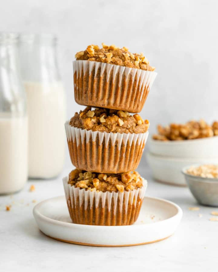 a stack of three vegan banana nut muffins on a white plate