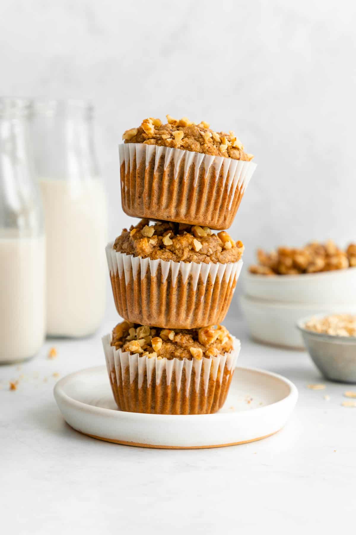 a stack of three vegan banana nut muffins on a white plate