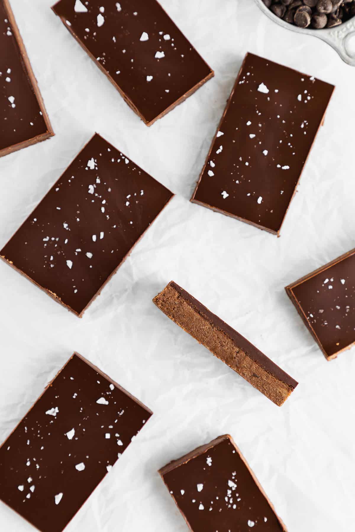 no bake chocolate protein bars on white parchment paper with one of them on its side