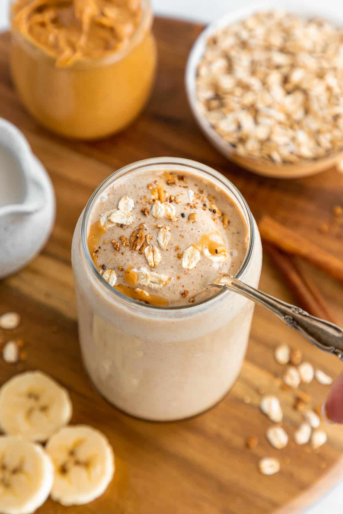 a spoon scooping into a peanut butter oatmeal smoothie inside a glass