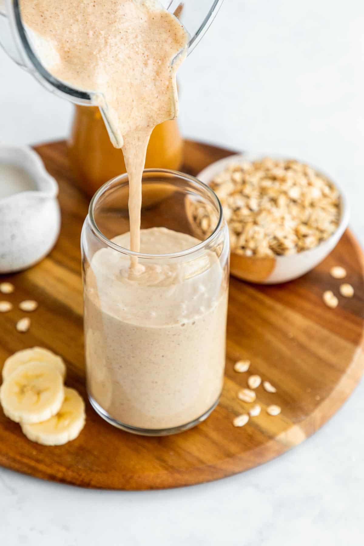 pouring an oatmeal smoothie into a glass out of a vitamix blender