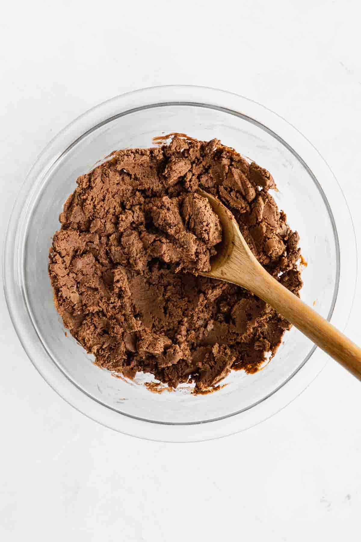 mixing chocolate dough for vegan protein bars in a glass bowl