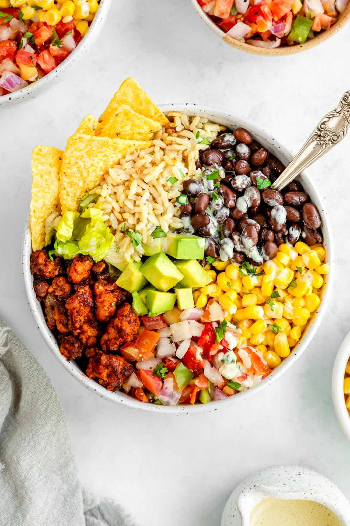 a vegan tempeh burrito bowl with a spoon sticking into it