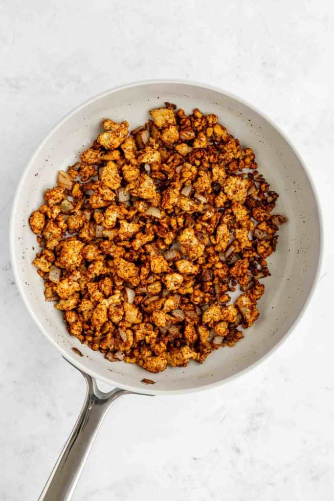 crumbled tempeh mixed with spices in a ceramic frying pan