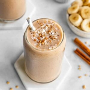 banana almond butter smoothie inside a glass surrounded by ingredients