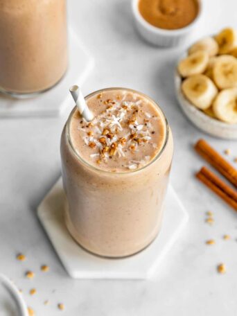 banana almond butter smoothie inside a glass surrounded by ingredients