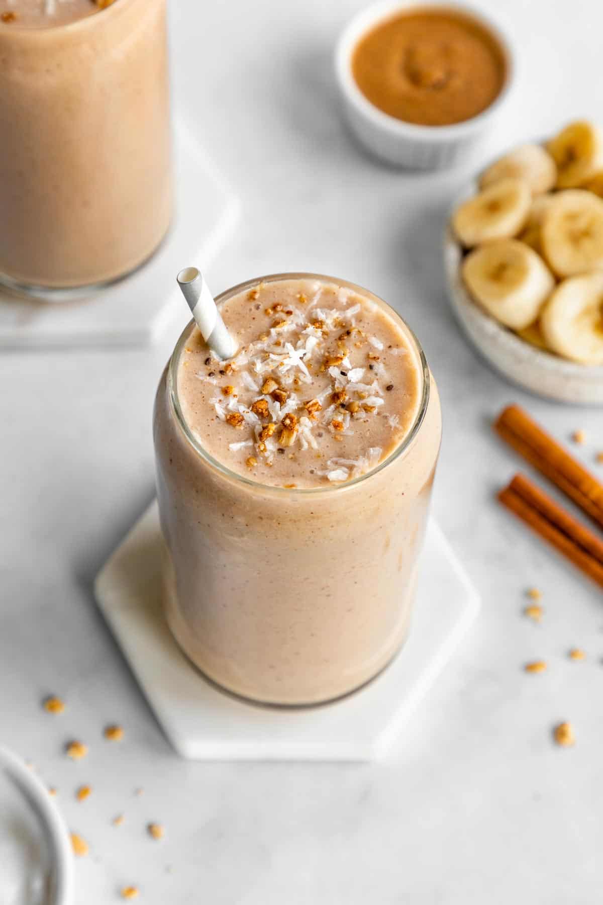 banana almond butter smoothie inside a glass surrounded by ingredients