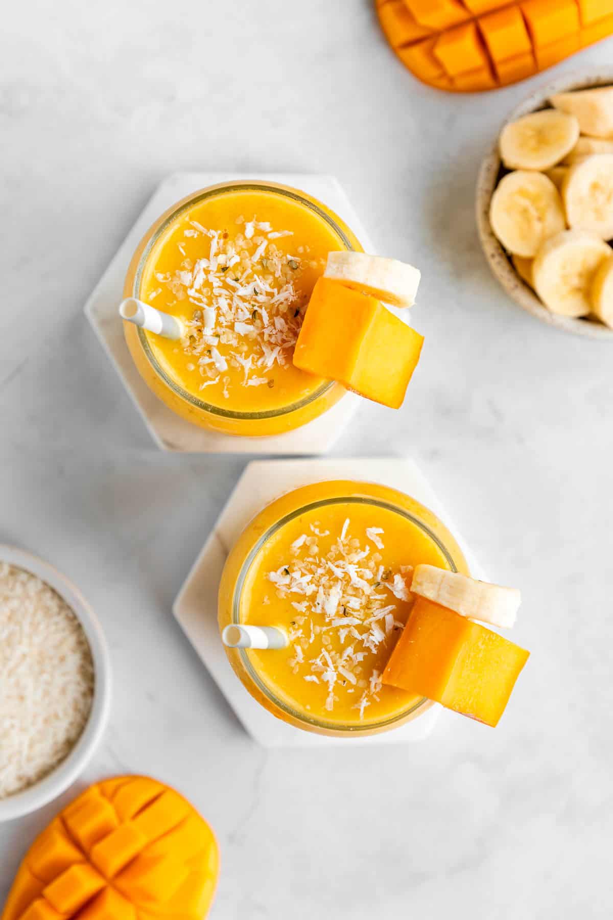 overhead photo of two glasses filled with mango banana smoothie