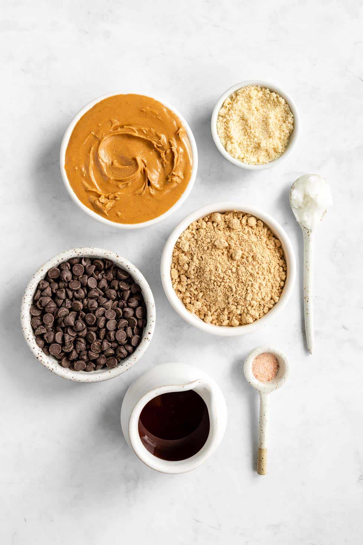 bowls of peanut butter, protein powder, chocolate chips, maple syrup, almond flour, vanilla, and salt