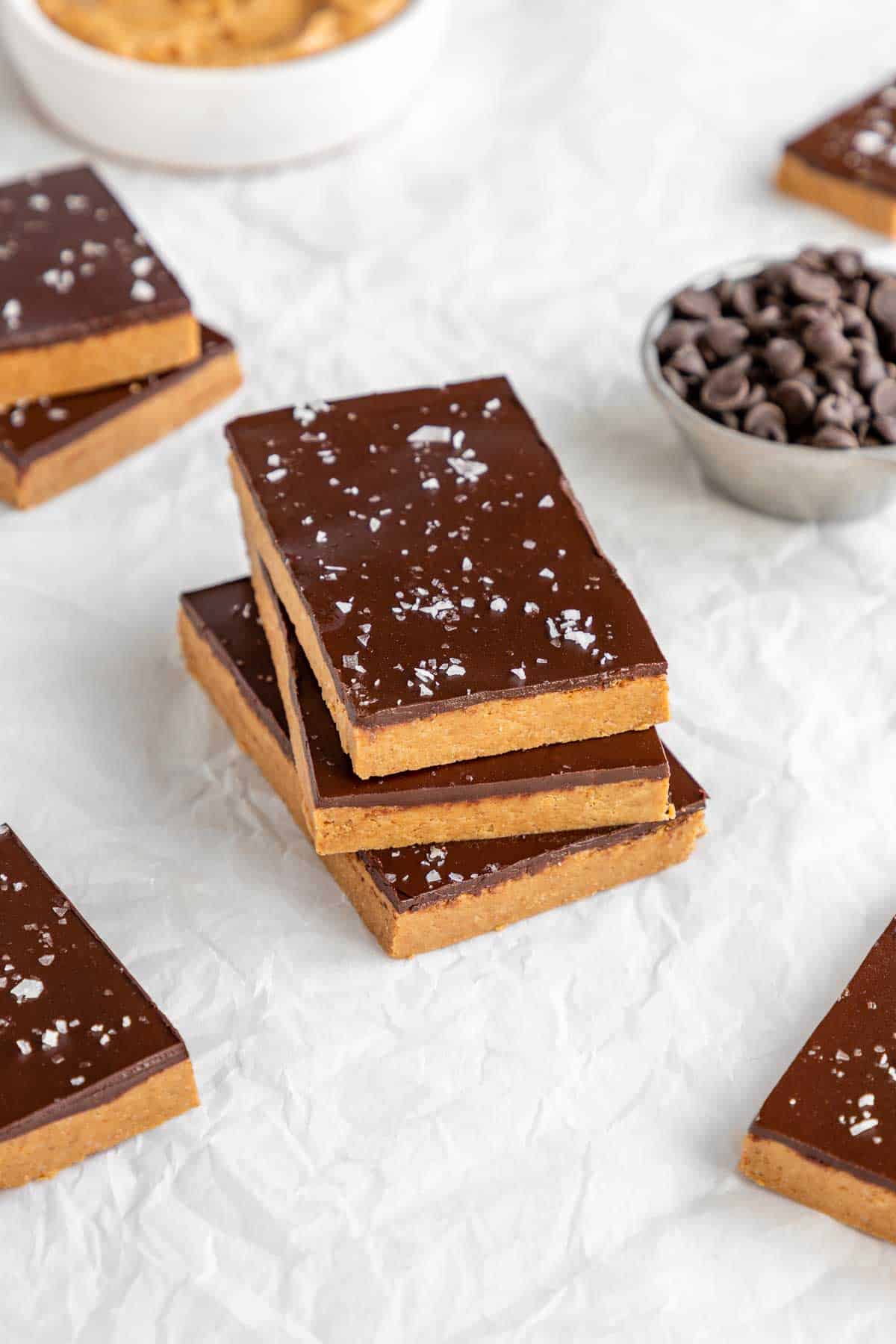 a stack of no bake chocolate peanut butter protein bars on white parchment paper