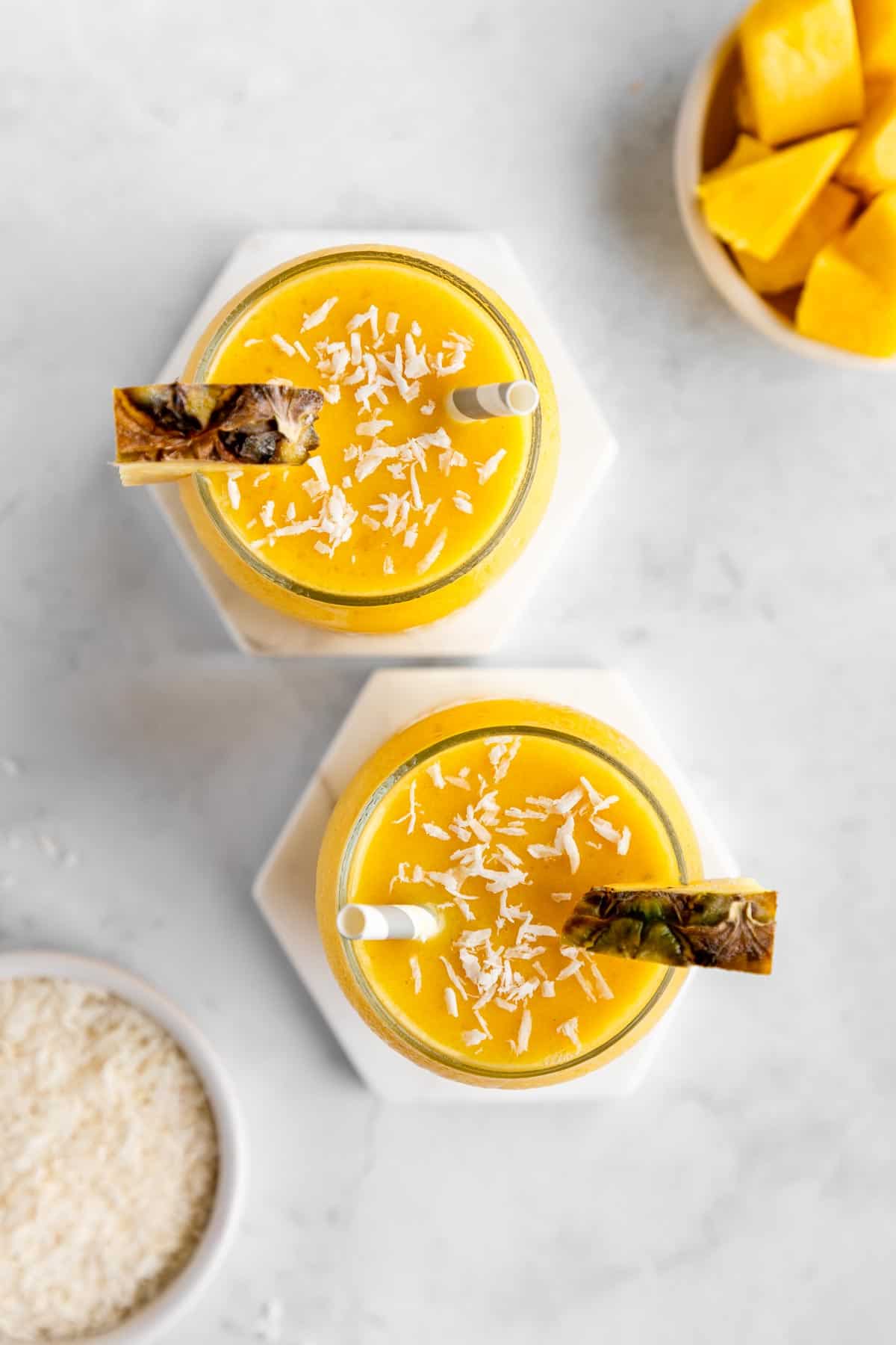 overhead photo of two pineapple coconut smoothie glasses