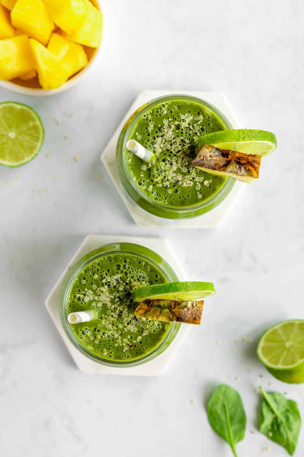 overhead photo of two glasses filled with pineapple green smoothies