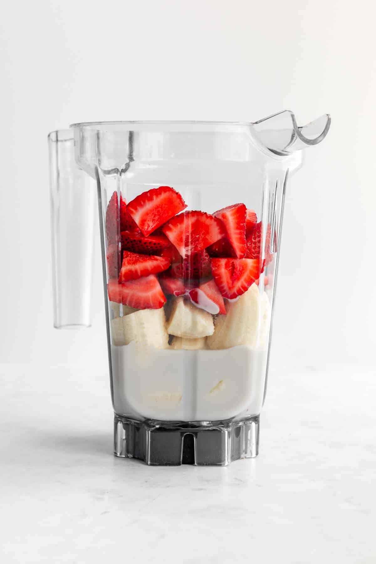 strawberries, banana, and almond milk inside a vitamix blender