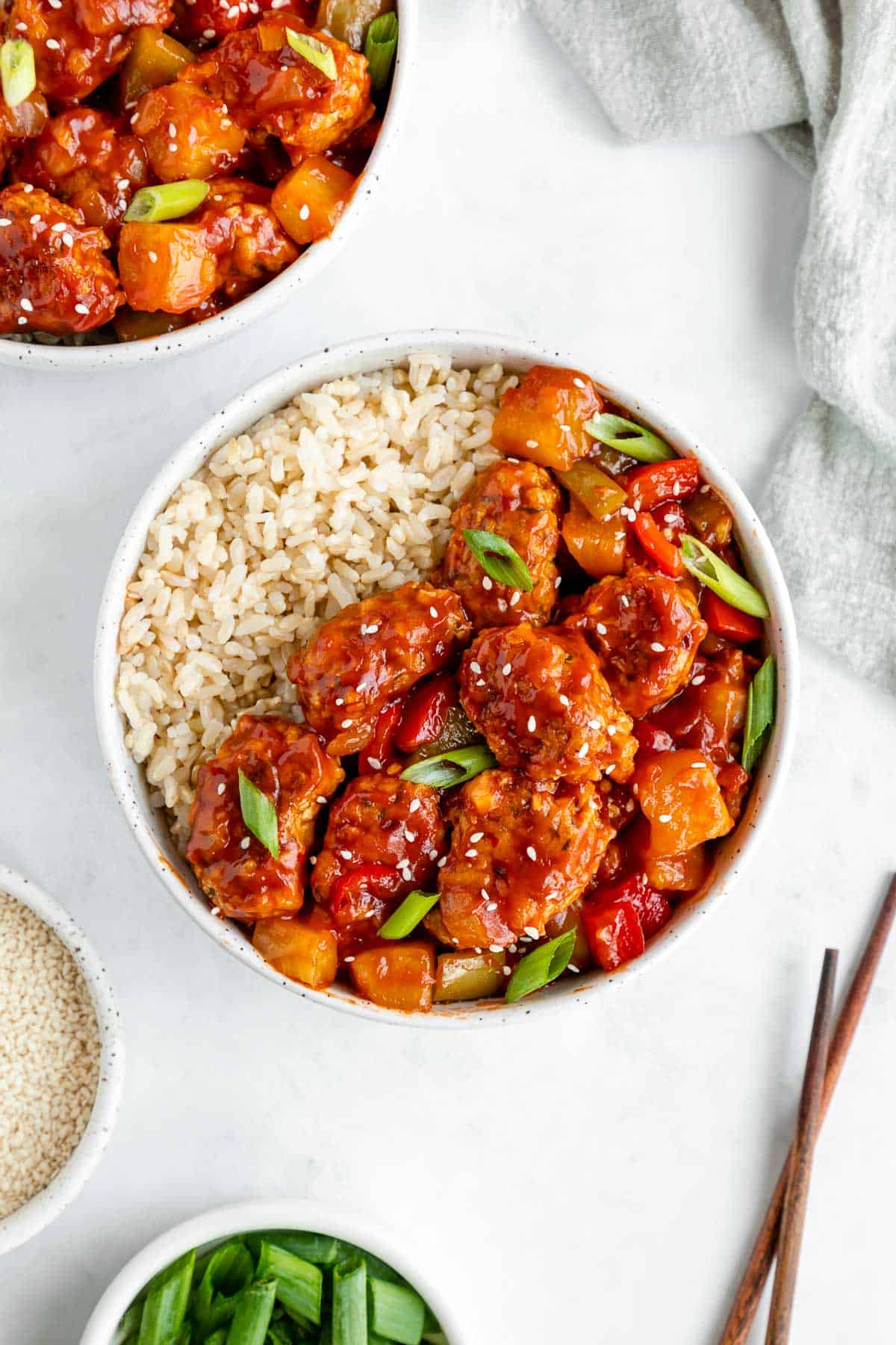 two bowls filled with vegan sweet and sour pork and brown rice