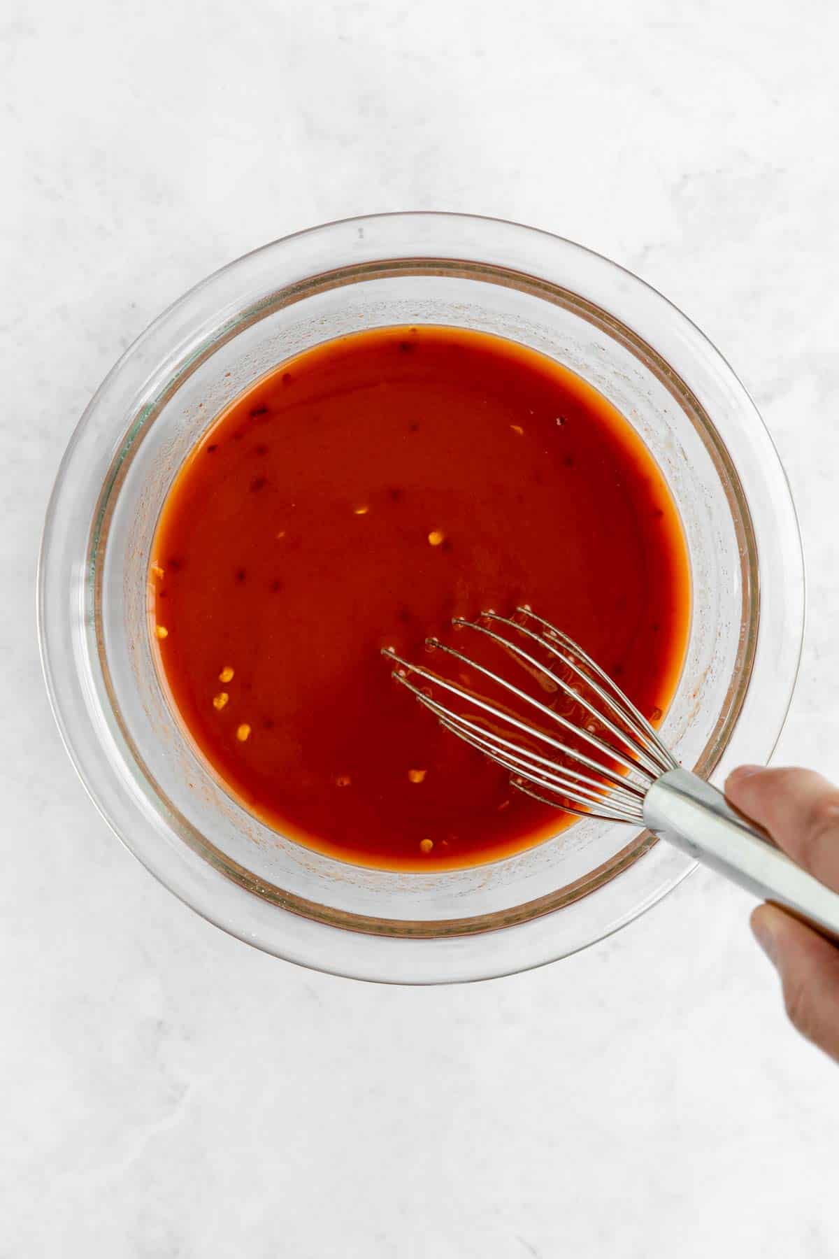 whisking homemade sweet and sour sauce in a bowl