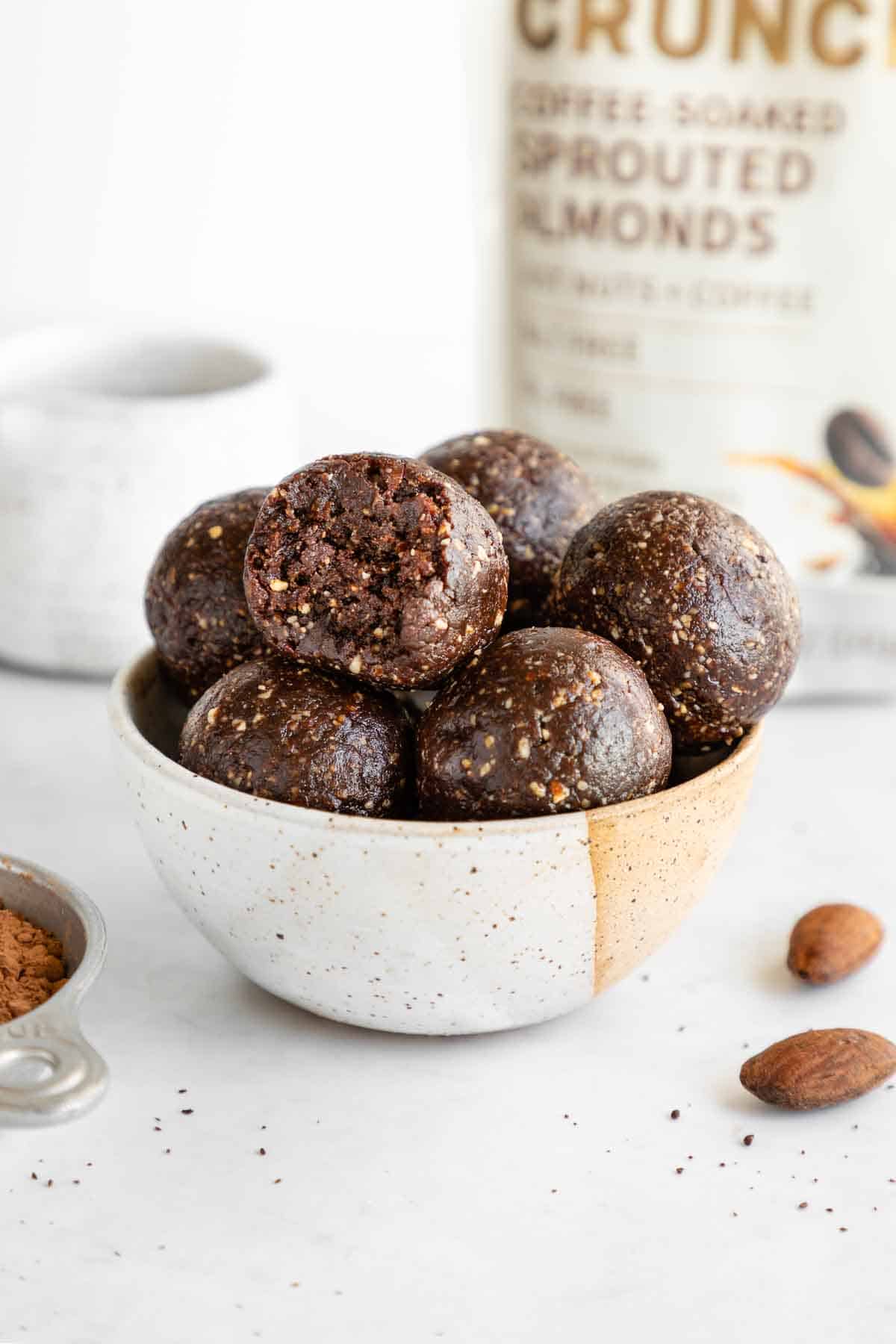 mocha energy balls inside a small ceramic bowl with a bite taken out of the middle one